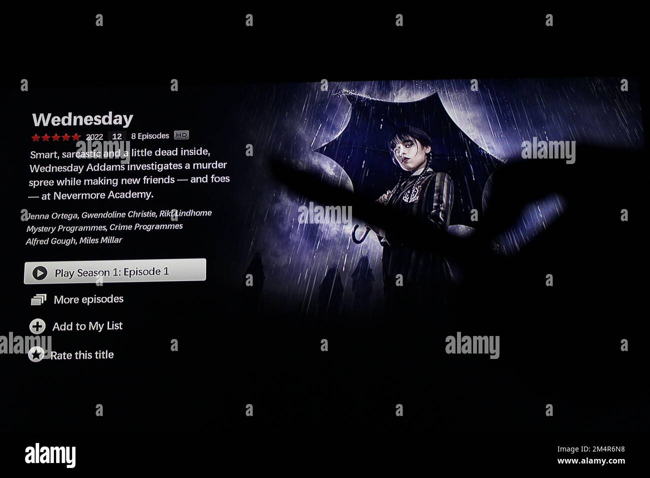 Die Netflix App auf dem fernsehbildschirm zeigt die Fernsehserie Mittwoch mit dem Schatten einer Fernbedienung, die kurz vor Staffel 1, Folge 1, steht Stockfoto