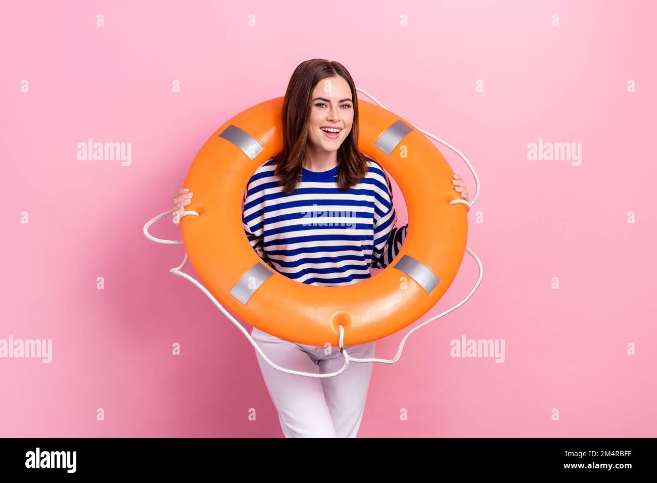 Foto eines fröhlichen, netten Mädchenlächelns, halten Sie den aufblasbaren Kreisring isoliert auf pinkfarbenem Hintergrund Stockfoto