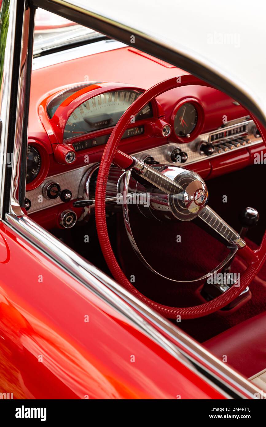 Lenkrad und Armaturenbrett eines roten Ford Thunderbird aus dem Jahr 1955 durch ein offenes Fenster. Stockfoto