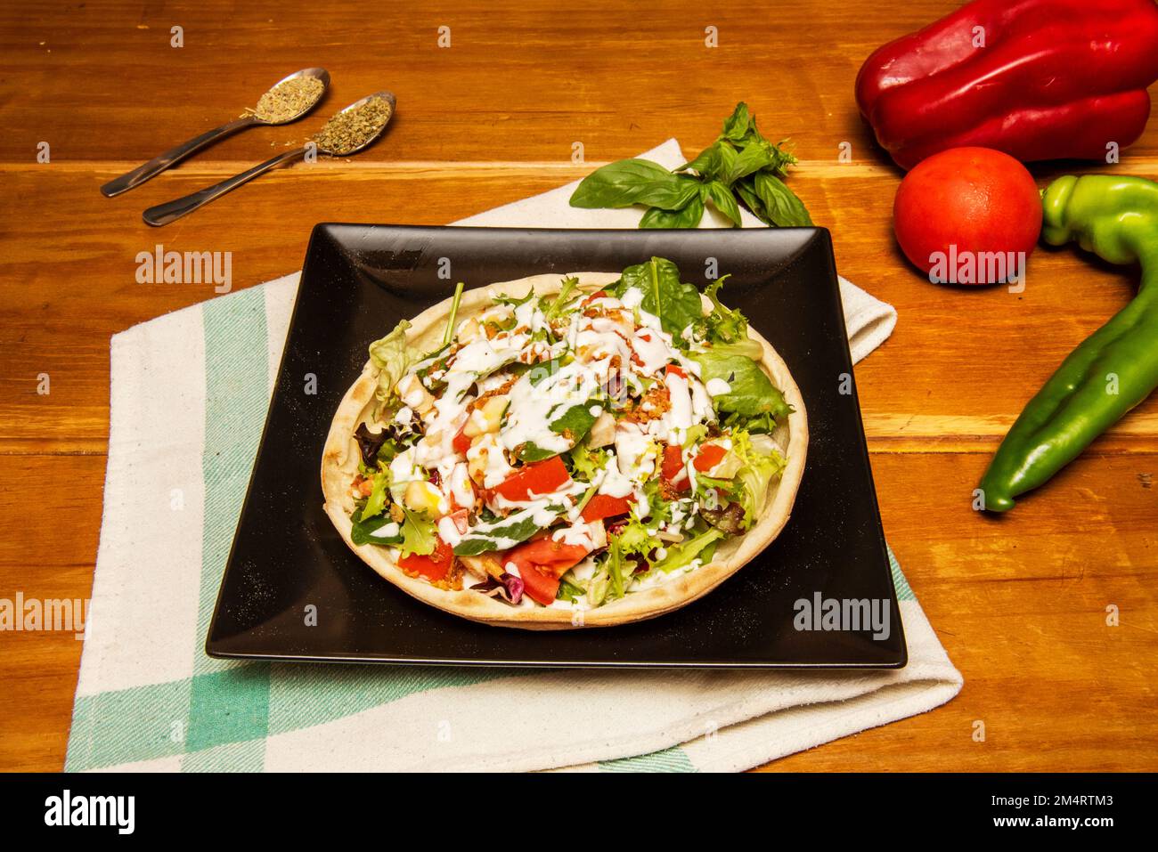 Eine Art Salatpizza mit viel Soße und Salat mit Tomaten Stockfoto