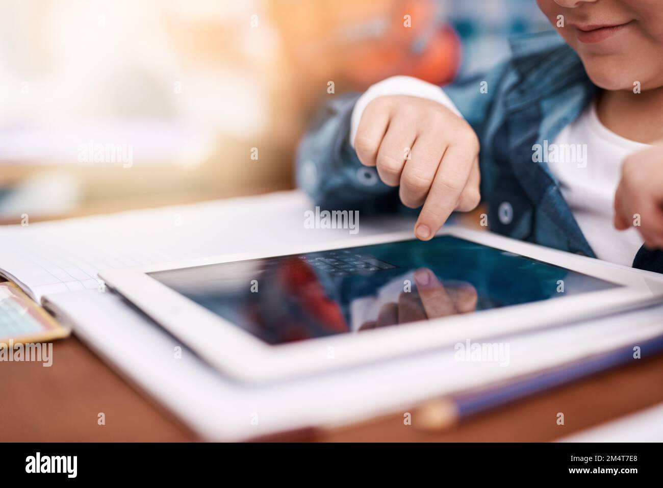 Ein Tastendruck genügt. Ein nicht wiedererkennbares Grundschüler, das im Klassenzimmer auf einem digitalen Tablet surft. Stockfoto