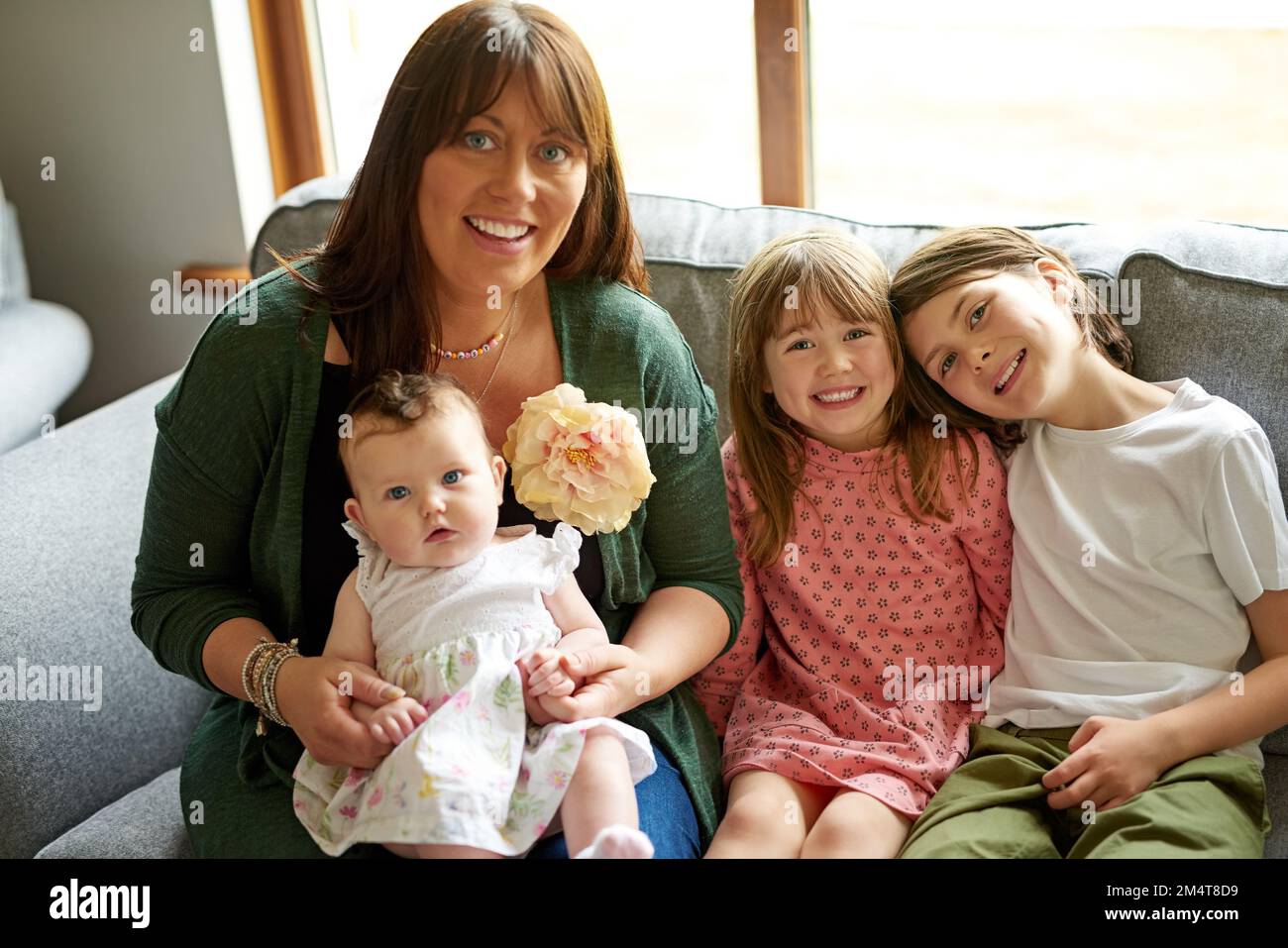 Eine große, gesegnete Familie. Porträt einer Mutter, die sich mit ihren drei kleinen Kindern zu Hause anfreundet. Stockfoto