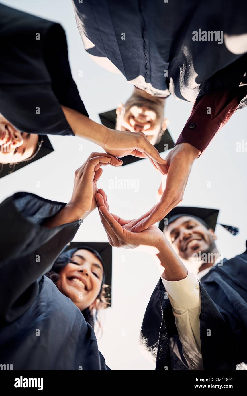 Wir wollen nur eine bessere Welt erschaffen. Nahaufnahme einer Gruppe von Schülern, die sich am Tag der Abschlussfeier in einem Kreis zusammenschließen. Stockfoto