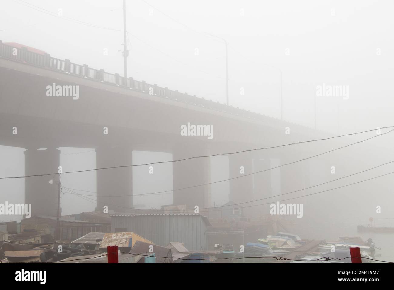 Garagen für Boote im Nebel unter einer Brücke am dnieper River am Morgen im Herbst Stockfoto