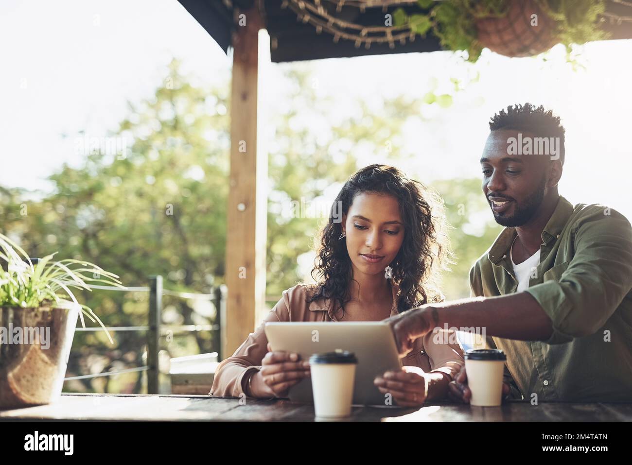 Dieses Online-Menü ist ziemlich interessant. Ein junges Paar, das ein digitales Tablet zusammen in einem Café benutzt. Stockfoto