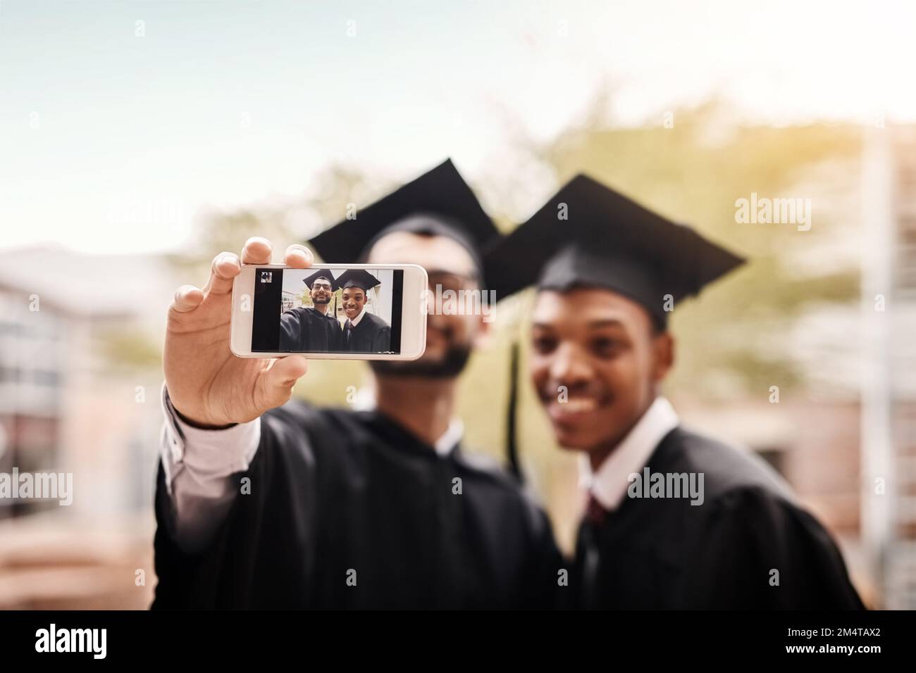 Sie sind beide stolz auf diesen Moment in ihrem Leben. Männliche Studenten machen ein Foto am Tag der Uni-Abschlussfeier. Stockfoto