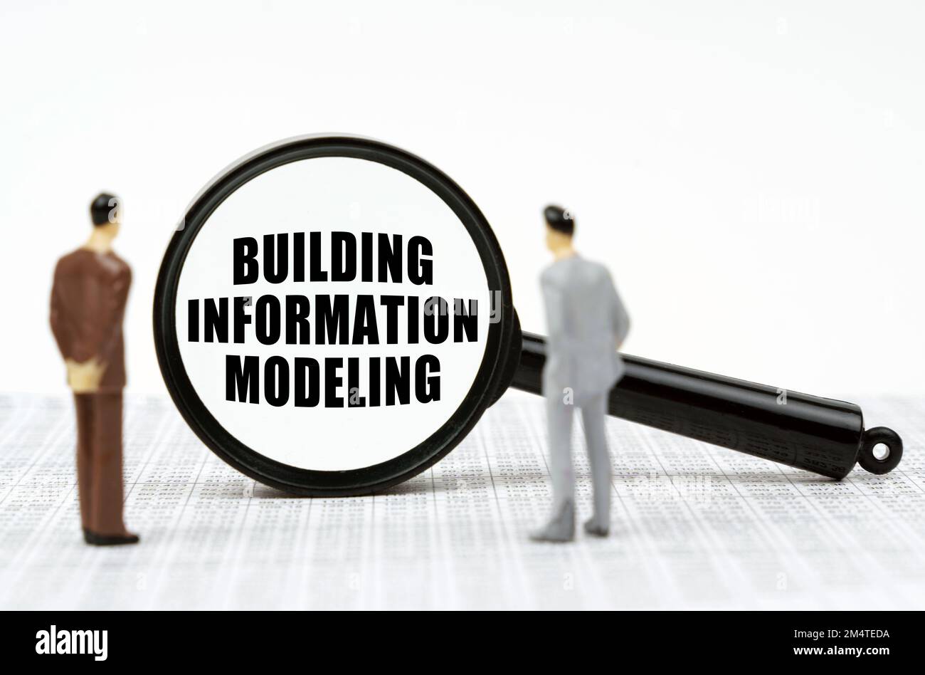 Geschäfts- und Finanzkonzept. In den Finanzberichten finden sich Miniaturzahlen von Geschäftsleuten und eine Lupe mit der Inschrift "Buildi" Stockfoto