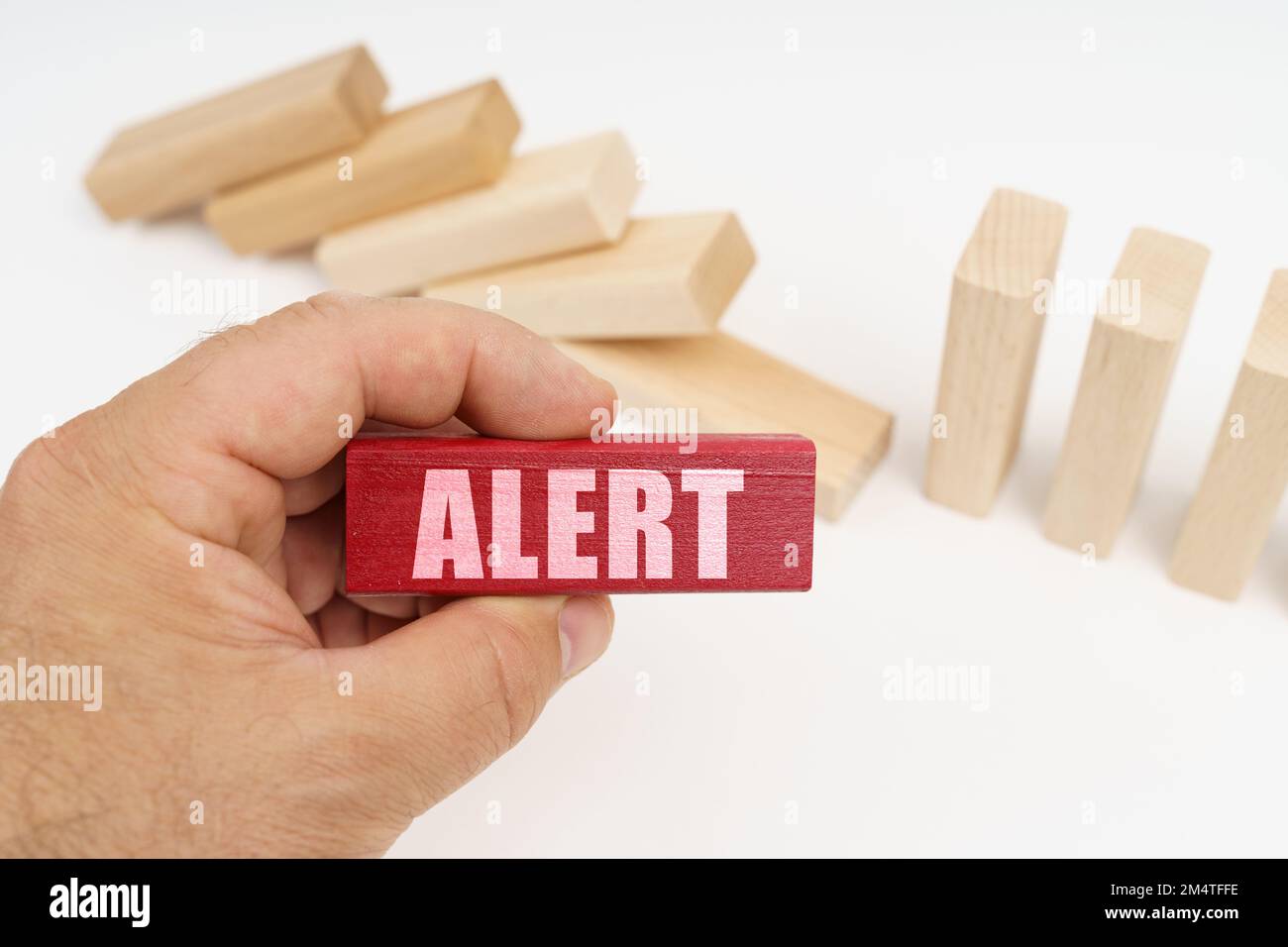 Geschäfts- und Finanzkonzept. Im Vordergrund, eine Hand mit einem roten Holzblock und der Inschrift - ACHTUNG, im Hintergrund, heruntergefallene Holzblöcke. Stockfoto