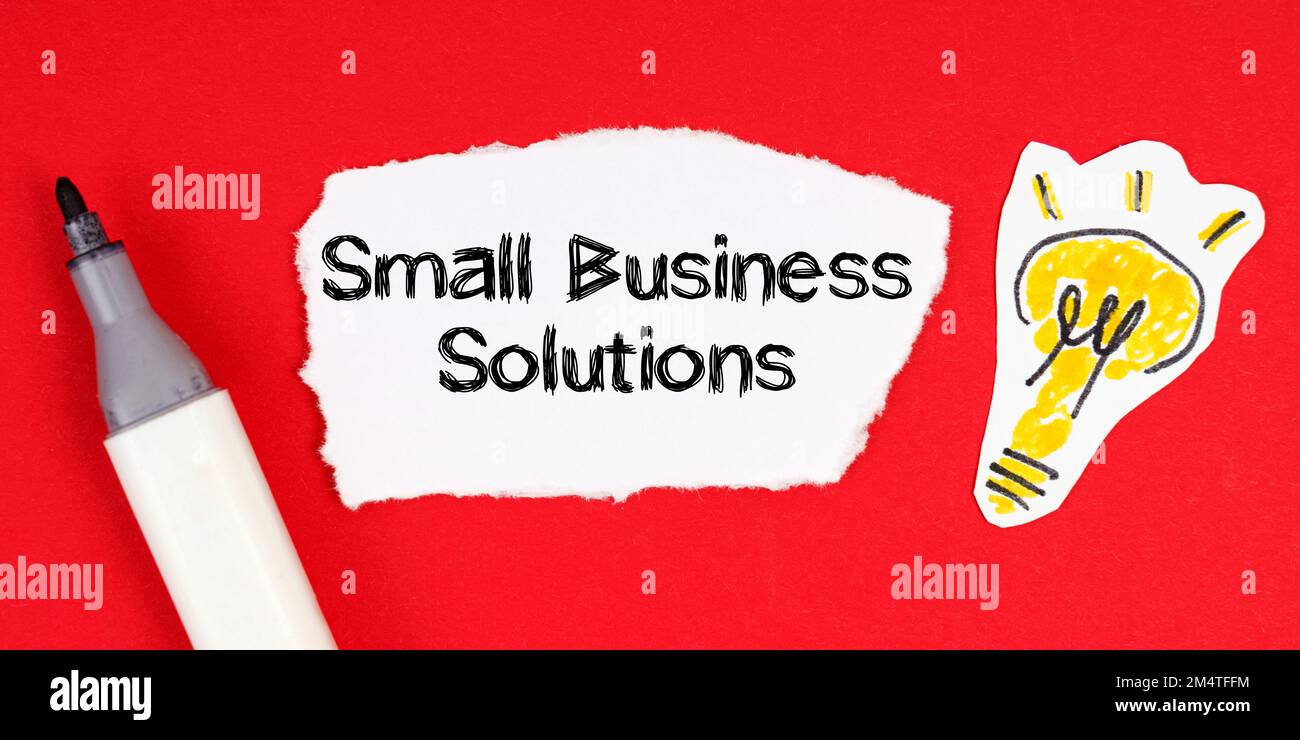 Geschäftskonzept und -Idee. Legen Sie auf einer roten Oberfläche eine Markierung, eine Zeichnung einer Glühbirne und ein zerrissenes Papier mit der Aufschrift „Small Business Solutions“ Stockfoto