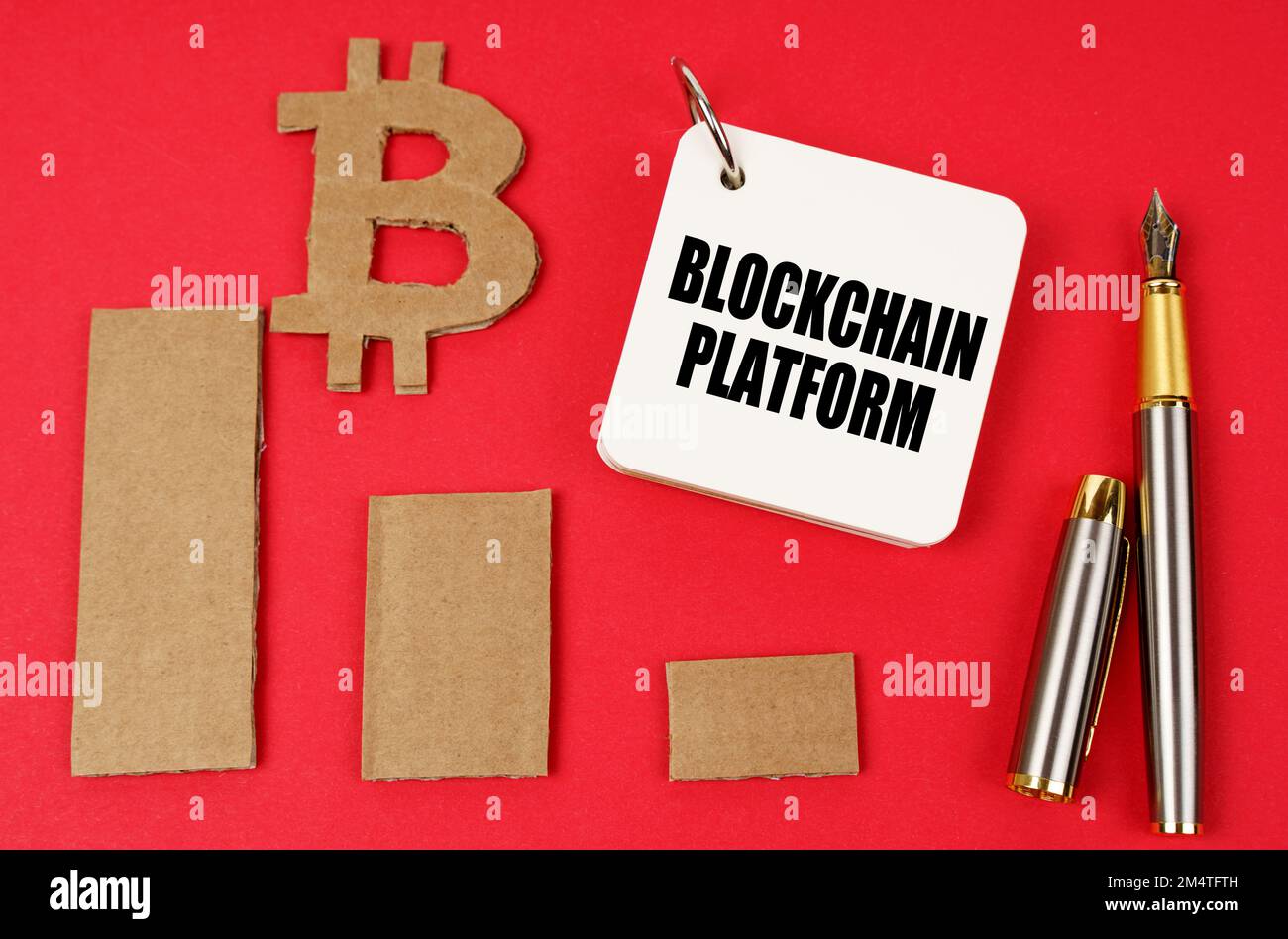 Business- und Bitcoin-Konzept. Auf einer roten Oberfläche liegen ein Bitcoin-Symbol, ein Diagramm, ein Stift und ein Notizblock mit der Aufschrift – Blockchain-Plattform Stockfoto
