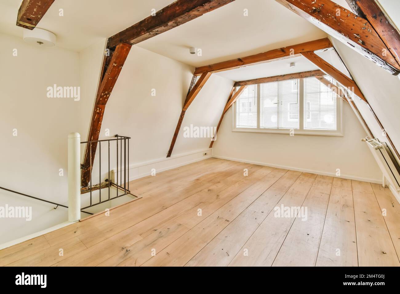 Ein Zimmer im Dachgeschoss-Stil mit Holzfußboden und freiliegenden Balken an der Decke in diesem Haus ist sehr gut eingerichtet Stockfoto