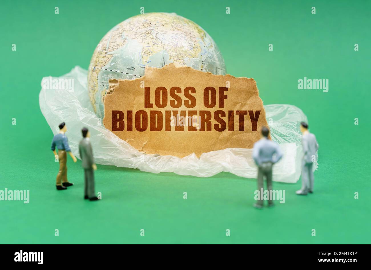 Ökologisches Konzept. Auf einem grünen Hintergrund auf einer Plastiktüte ist ein Globus und ein Schild mit der Inschrift - Verlust der Artenvielfalt. Fast unscharf Stockfoto