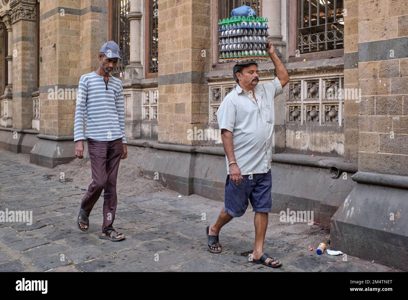 Ein Portier mit Eierkisten auf dem Kopf, am Chhatrapati Shivaji Maharaj Terminus (CMST) in Mumbai, Indien, um die Kisten mit dem Zug zu transportieren Stockfoto