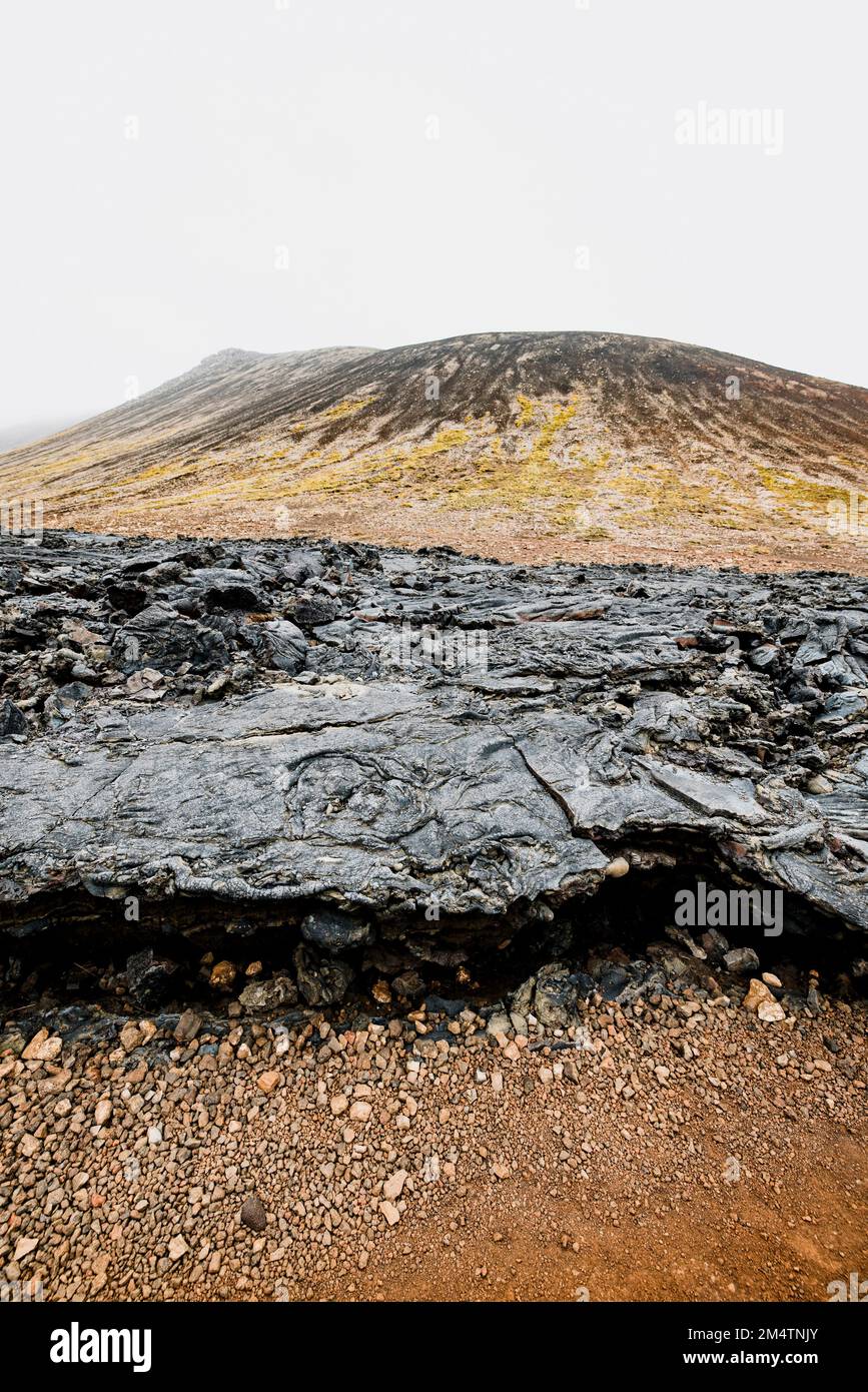 Vertikales Foto von Vulkangeländen in Island mit schwarzen vulkanischen Felsen und rotem Boden Stockfoto