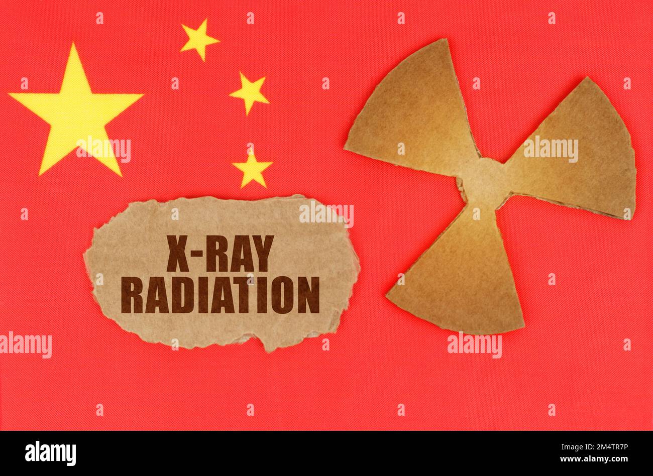 Industrie- und Strahlenbegriff. Auf der Flagge Chinas, das Symbol der Radioaktivität und zerrissener Karton mit der Aufschrift - Röntgenstrahlung Stockfoto