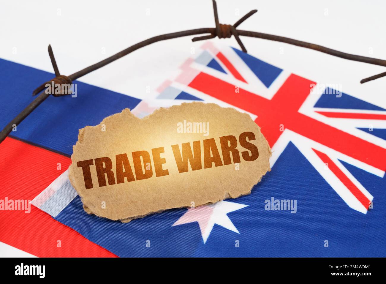 Politisches Konzept. Auf den Flaggen Australiens und Russlands liegt ein Pappteller mit der Inschrift "Handelskriege". Durch Stacheldraht getrennte Flaggen Stockfoto