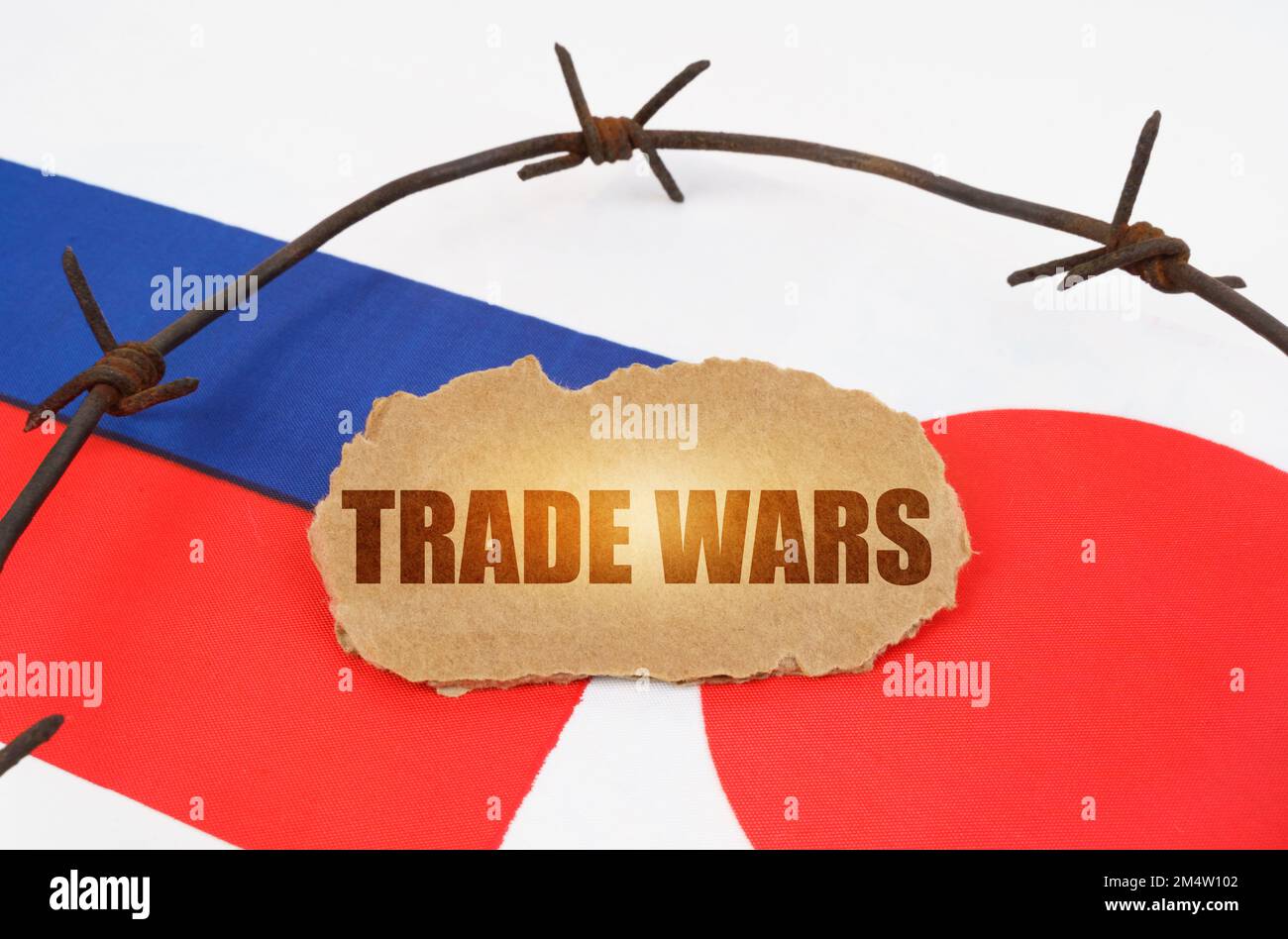 Politisches Konzept. Auf den Flaggen Japans und Russlands liegt ein Pappteller mit der Inschrift "Handelskriege". Durch Stacheldraht getrennte Flaggen Stockfoto
