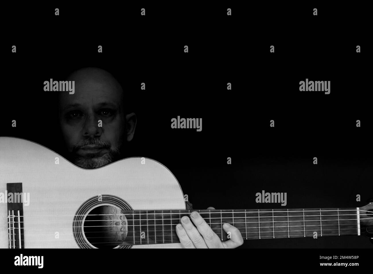 Eine Graustufenaufnahme eines charismatischen, kaukasischen männlichen Gitarrist Stockfoto