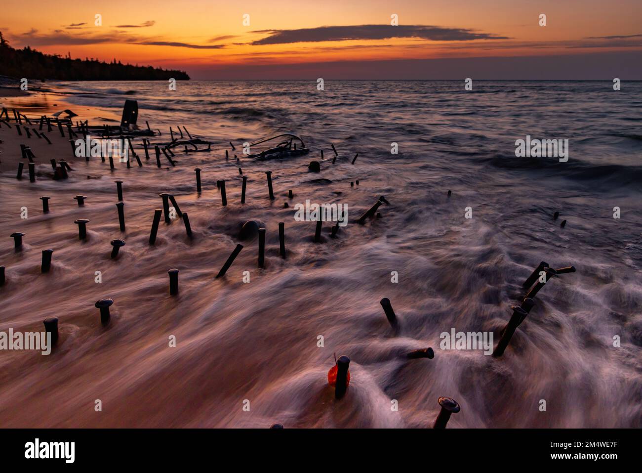 Lake Superior Schiffswracks liegen an den Ufern, während die Wellen zwischen den Wrackteilen schweben, unter einem Sonnenuntergang der Great Lakes an der Graveyard Coast USA Stockfoto