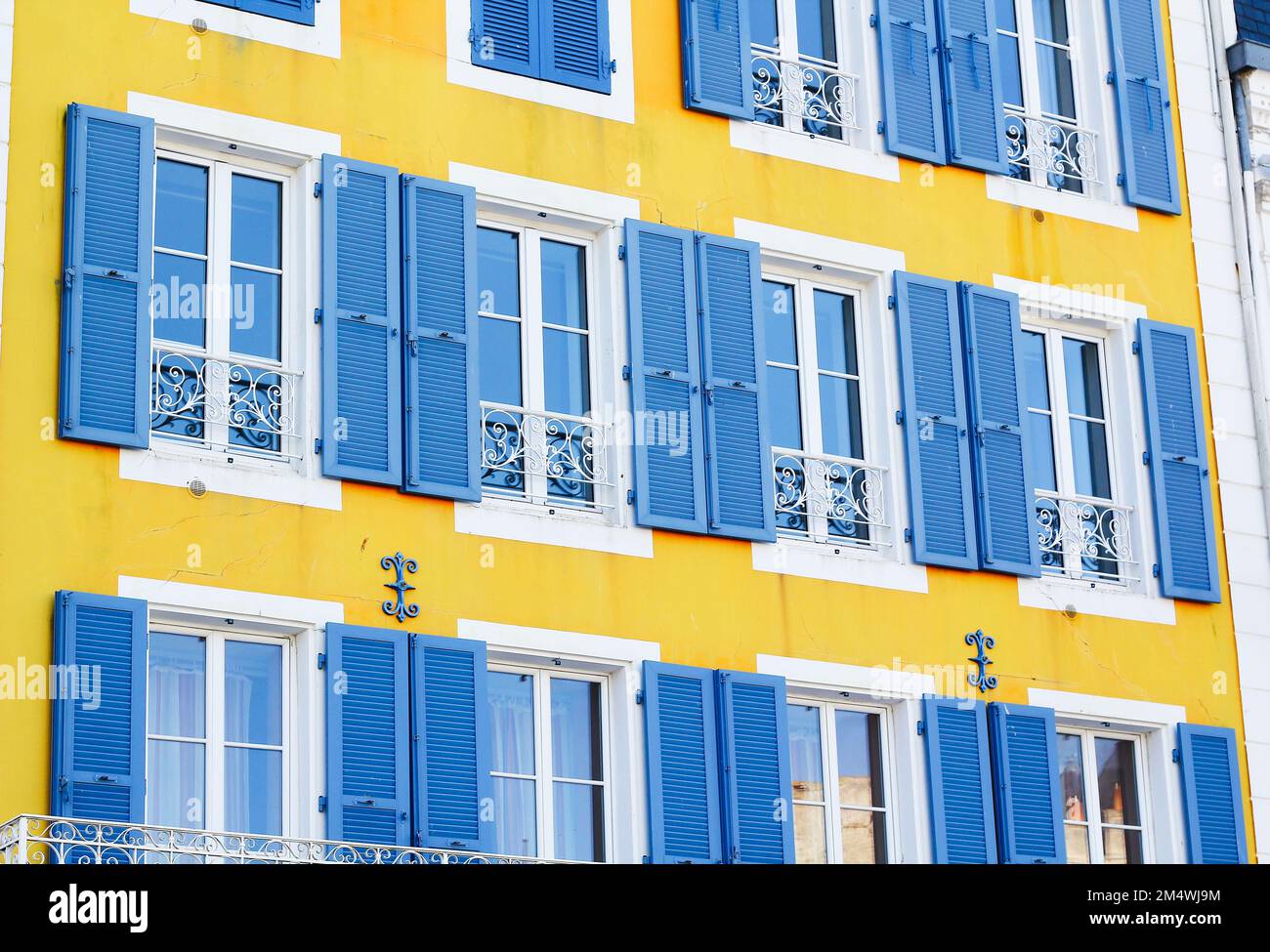 Hellgelbe Gebäudefassade mit blauen Fensterläden in Belle-île-en-Mer, Frankreich Stockfoto