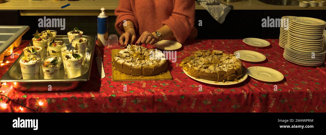 Der Tisch ist zu Weihnachten mit einem roten Tuch bedeckt, mit Apfelkuchen und Desserts wie Pudding Stockfoto