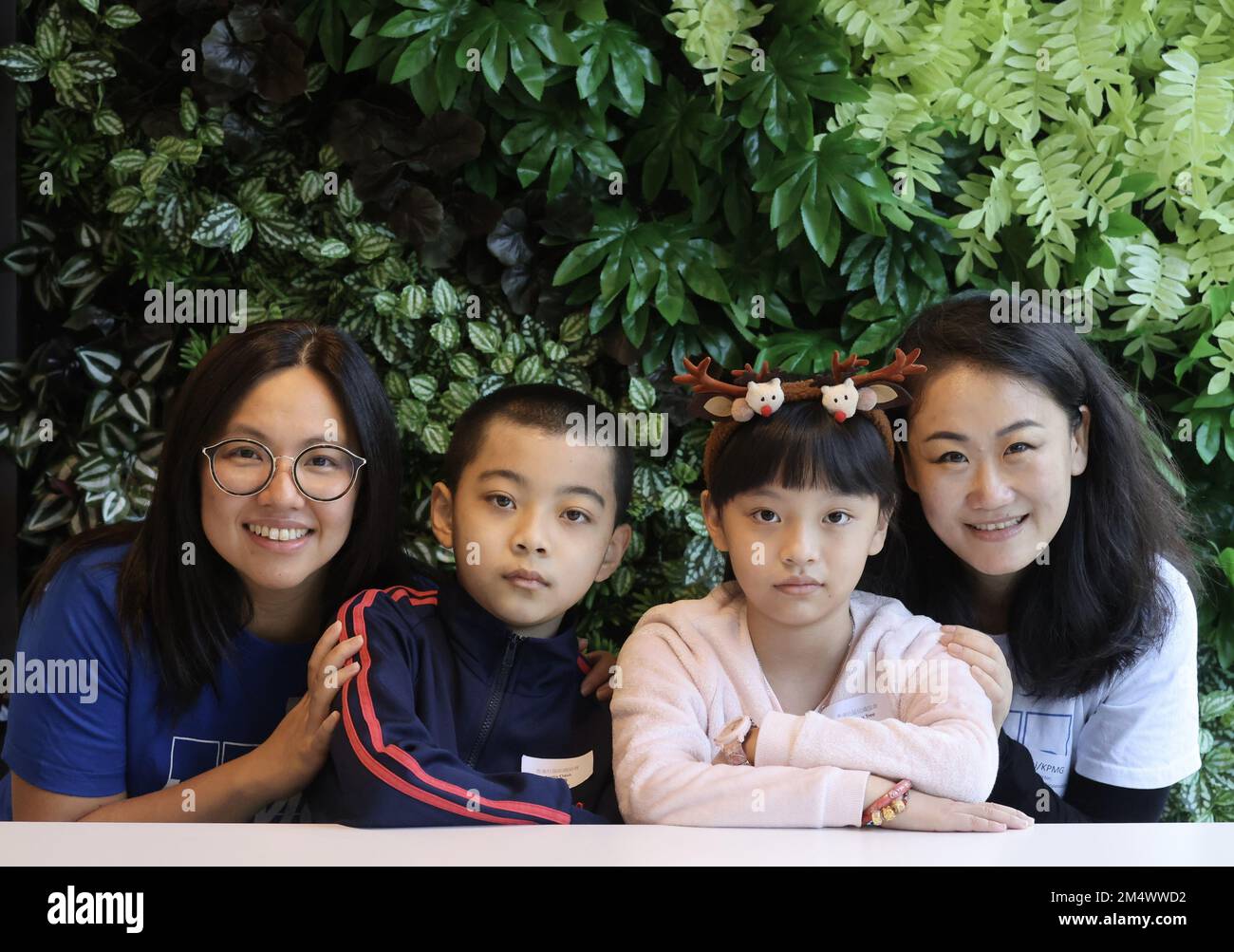 KPMGHH (L bis R) Partner Serene Seah-Tan und CSR Director of Social Responsibilties Zhang Chi, mit Kindern (L bis R) Thomas Wei Wentao und Christy Chan Li, bei der OSC KPMG-Veranstaltung English Reading Program mit Kindern von SOCO, in den KPMG Hang-Büros in Wong Chuk. 03DEC22 SCMP/Jonathan Wong Stockfoto