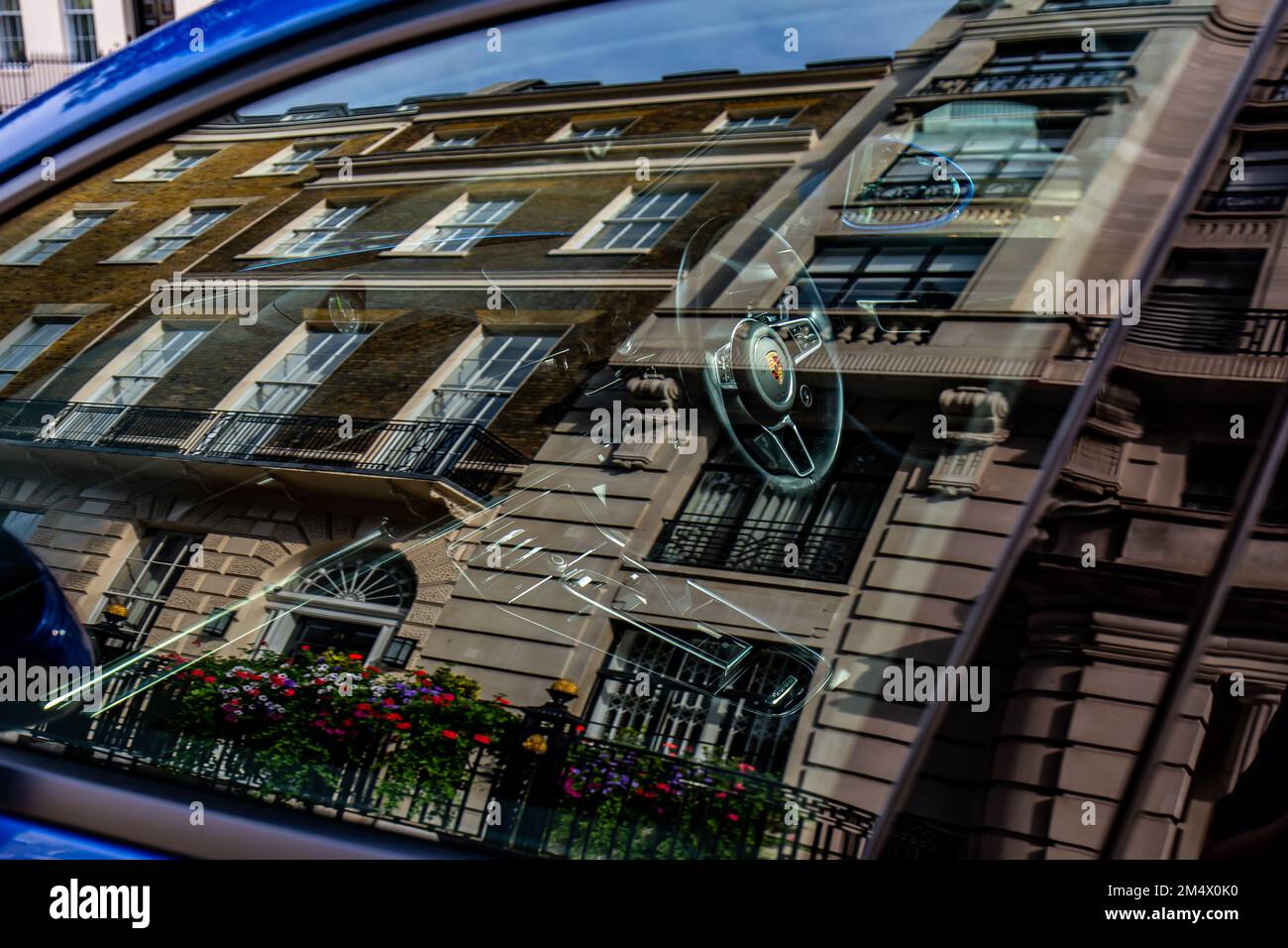 Ein wunderschöner Sportsalon, der vor Luxuswohnungen im Londoner West End parkt. Atemberaubende Spiegelung von Wohnungen im Fenster des Porsche Luxusautos Stockfoto