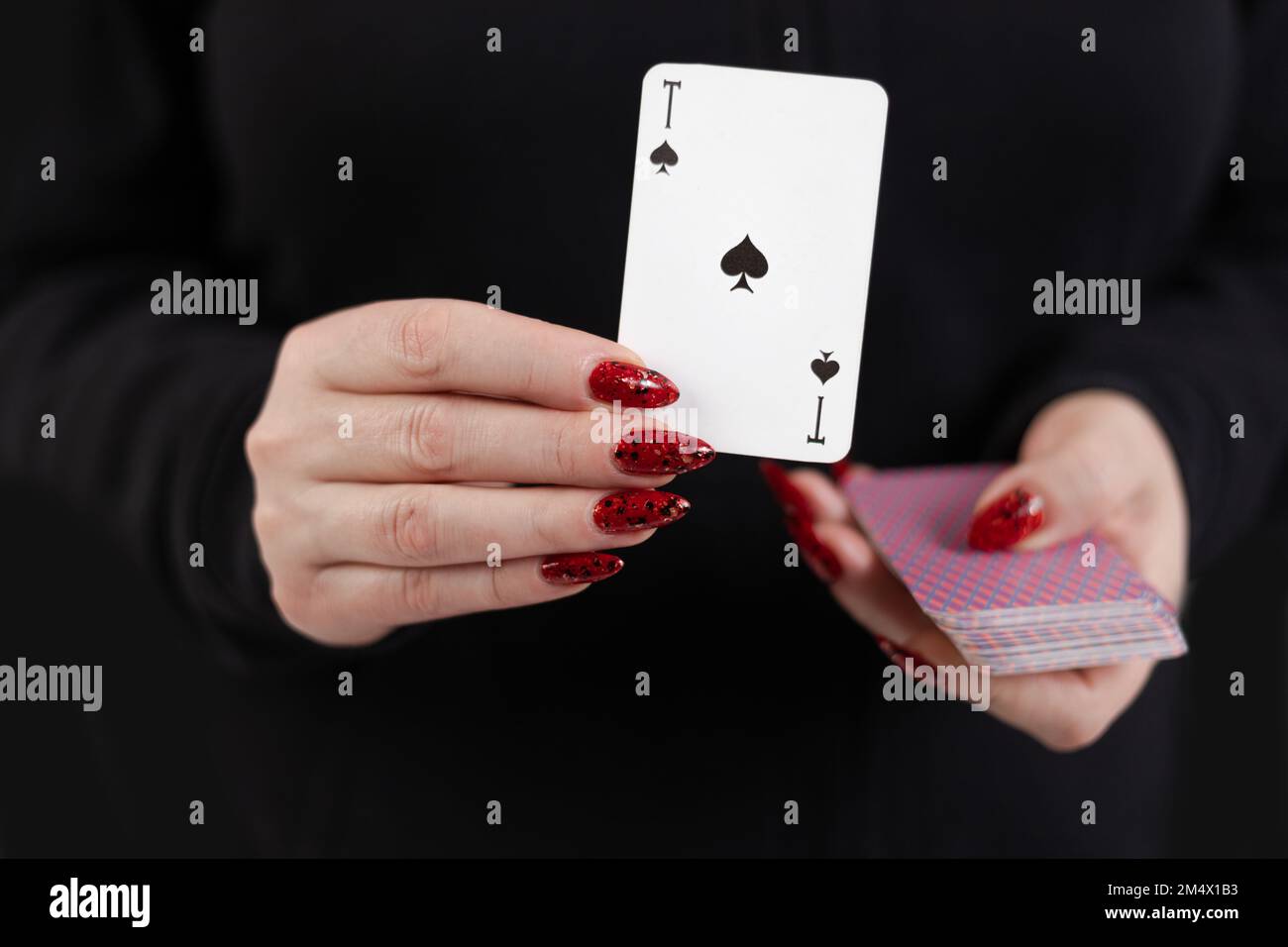 Weibliche Hände halten ein Kartenspiel und zeigen Tricks. Stockfoto