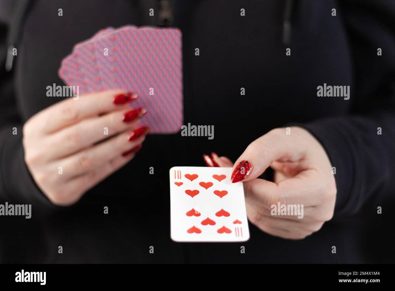 Weibliche Hände halten ein Kartenspiel und zeigen Tricks. Stockfoto