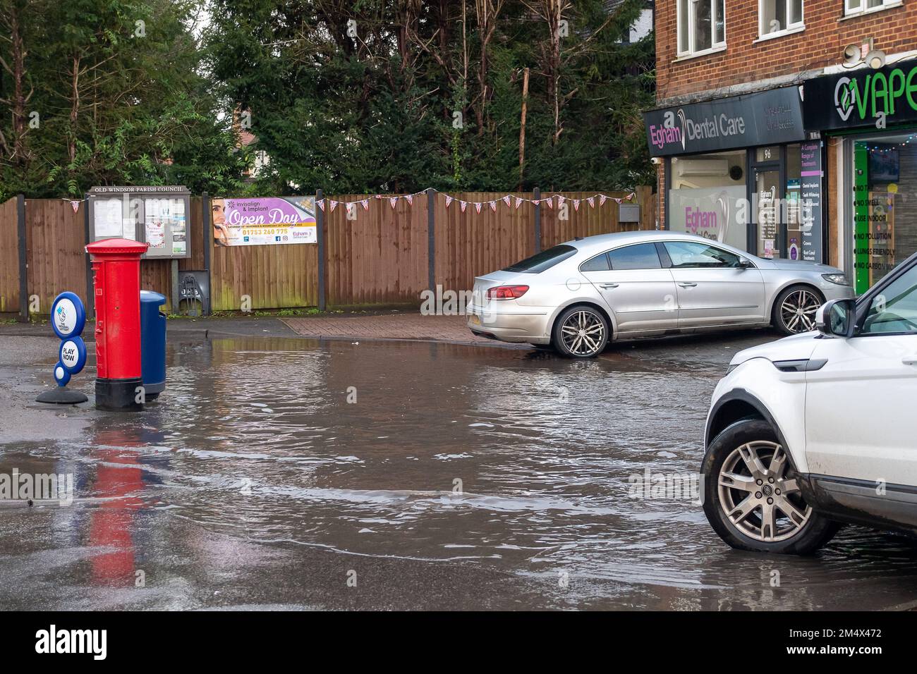 Old Windsor, Berkshire, Großbritannien. 23. Dezember 2022. Nach kürzlichen starken Regenfällen wurde heute ein Parkplatz vor einer Parade von Geschäften auf der Straight Road in Old Windsor überflutet. Kredit: Maureen McLean/Alamy Live News Stockfoto