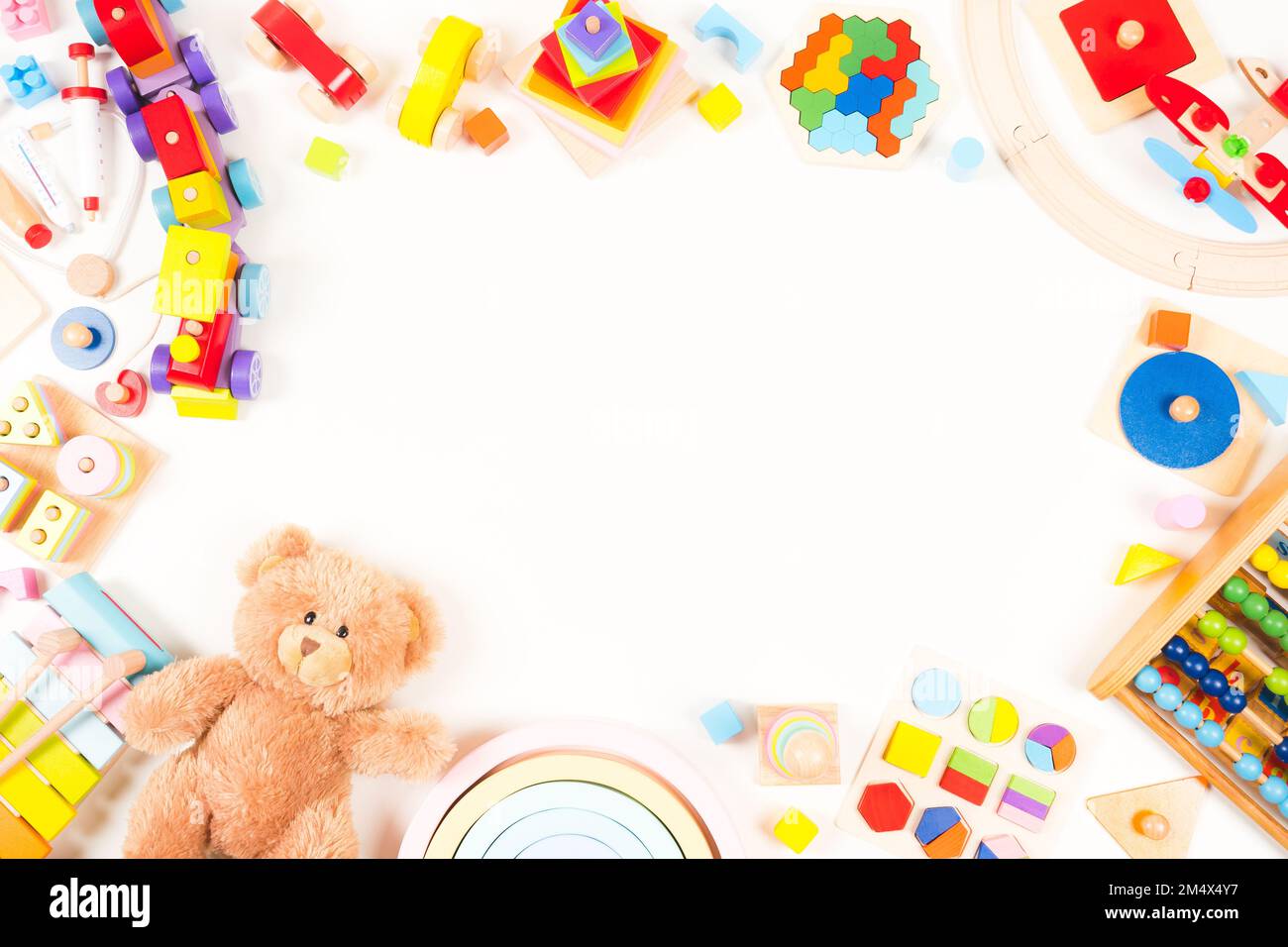 Hintergrund für Babyspielzeug. Teddybär, pädagogisch, musikalisch, sensorisch, Sortier- und Stapelspielzeug, Holzzug, Regenbogen, farbenfrohes Gebäude Stockfoto