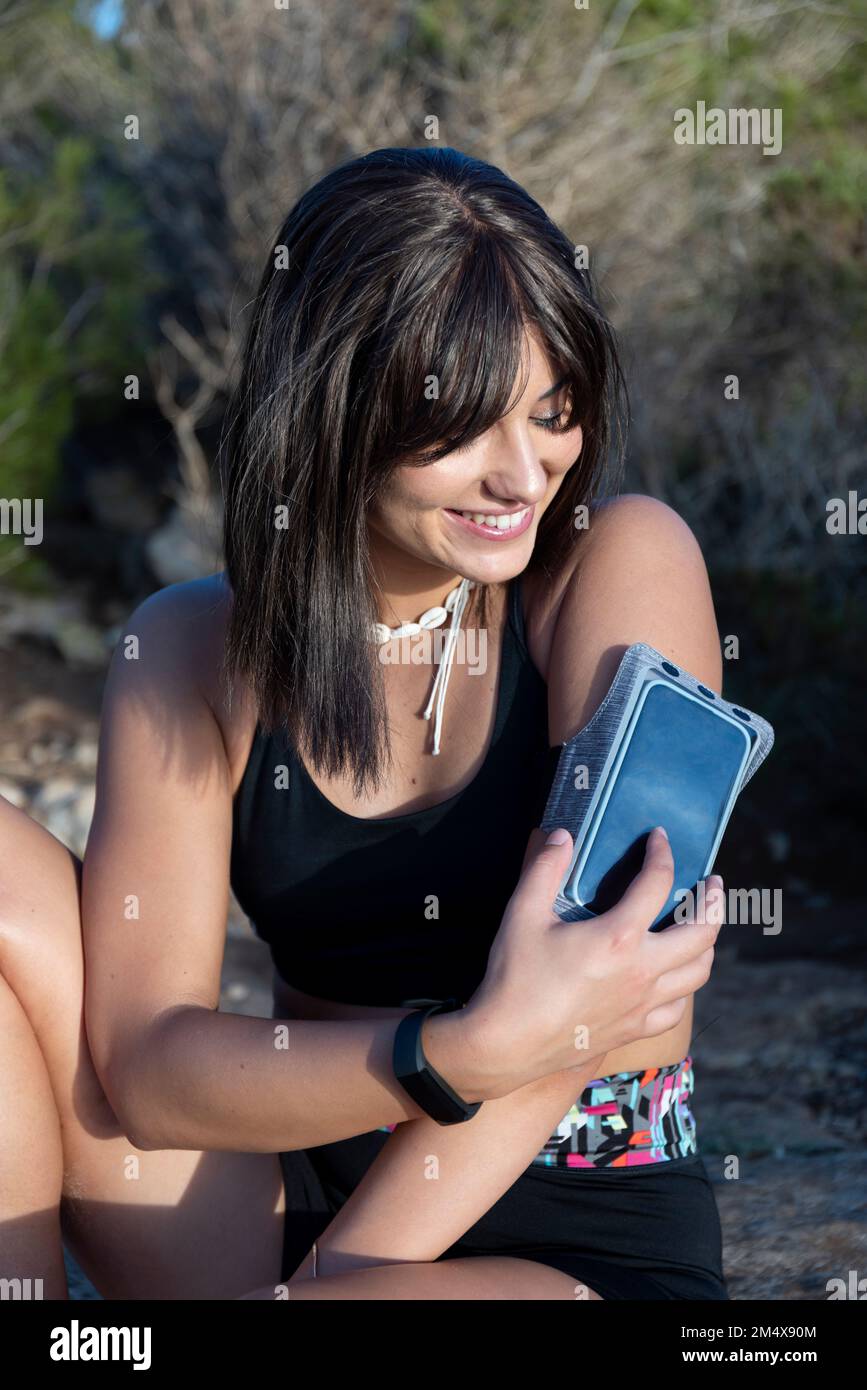 Frau, die den Bildschirm eines Smartphones am Armband berührt Stockfoto