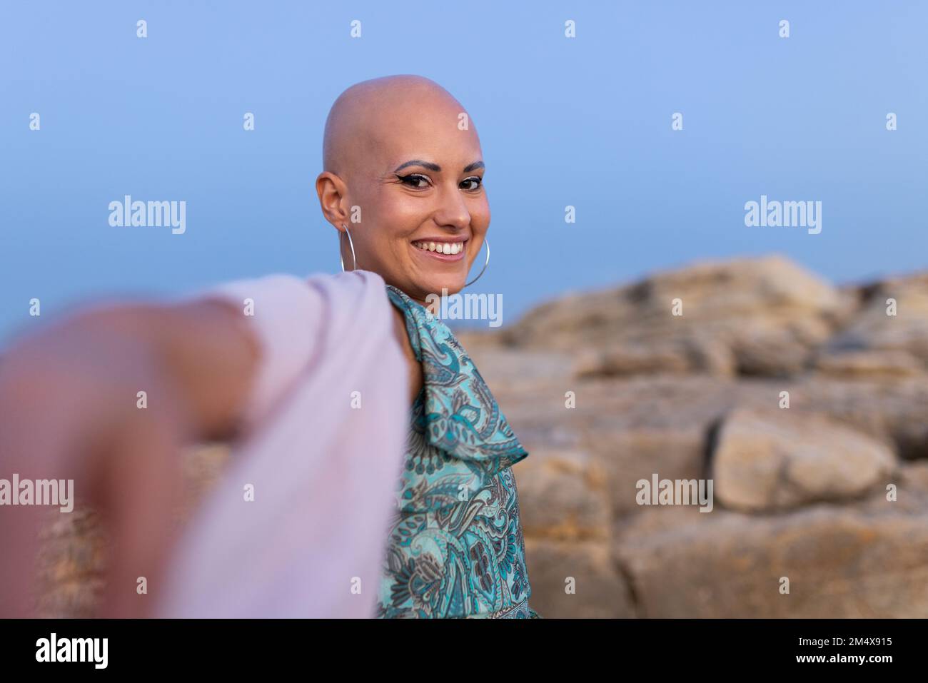Glückliche Frau mit Alopezie, die den Sonnenuntergang genießt Stockfoto