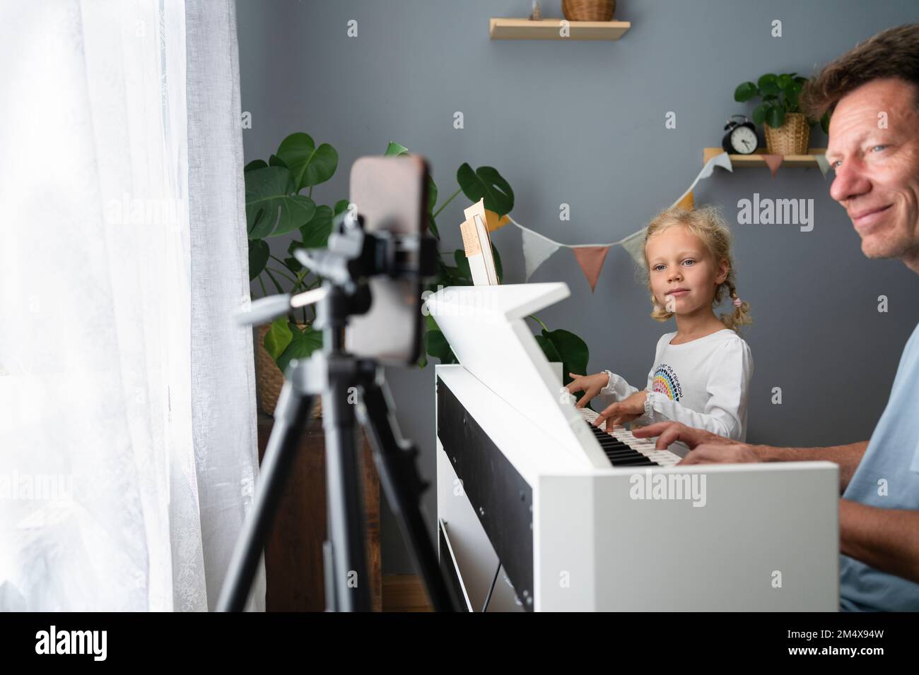 Vater und Tochter lernen zu Hause Klavier über das Mobiltelefon zu spielen Stockfoto