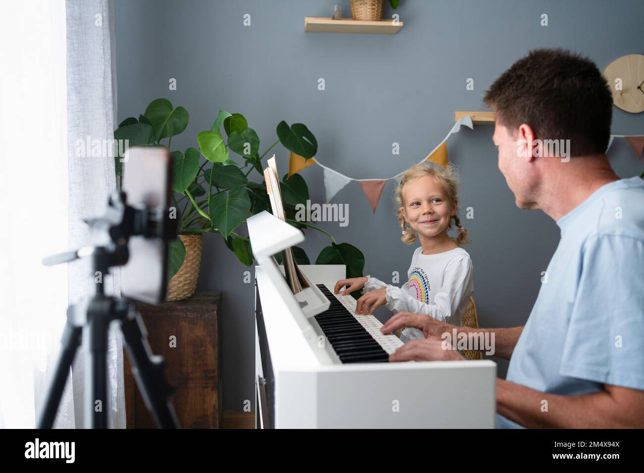 Lächelndes Mädchen, das mit Vater zu Hause Klavier spielt Stockfoto