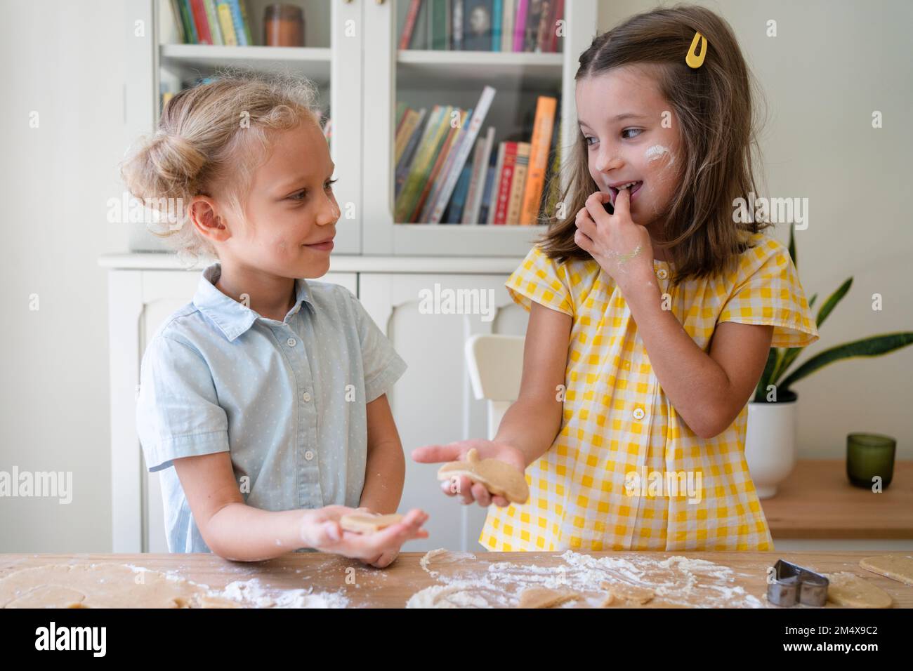 Glückliche Mädchen, die zu Hause Kekse mit Teig zubereiten Stockfoto
