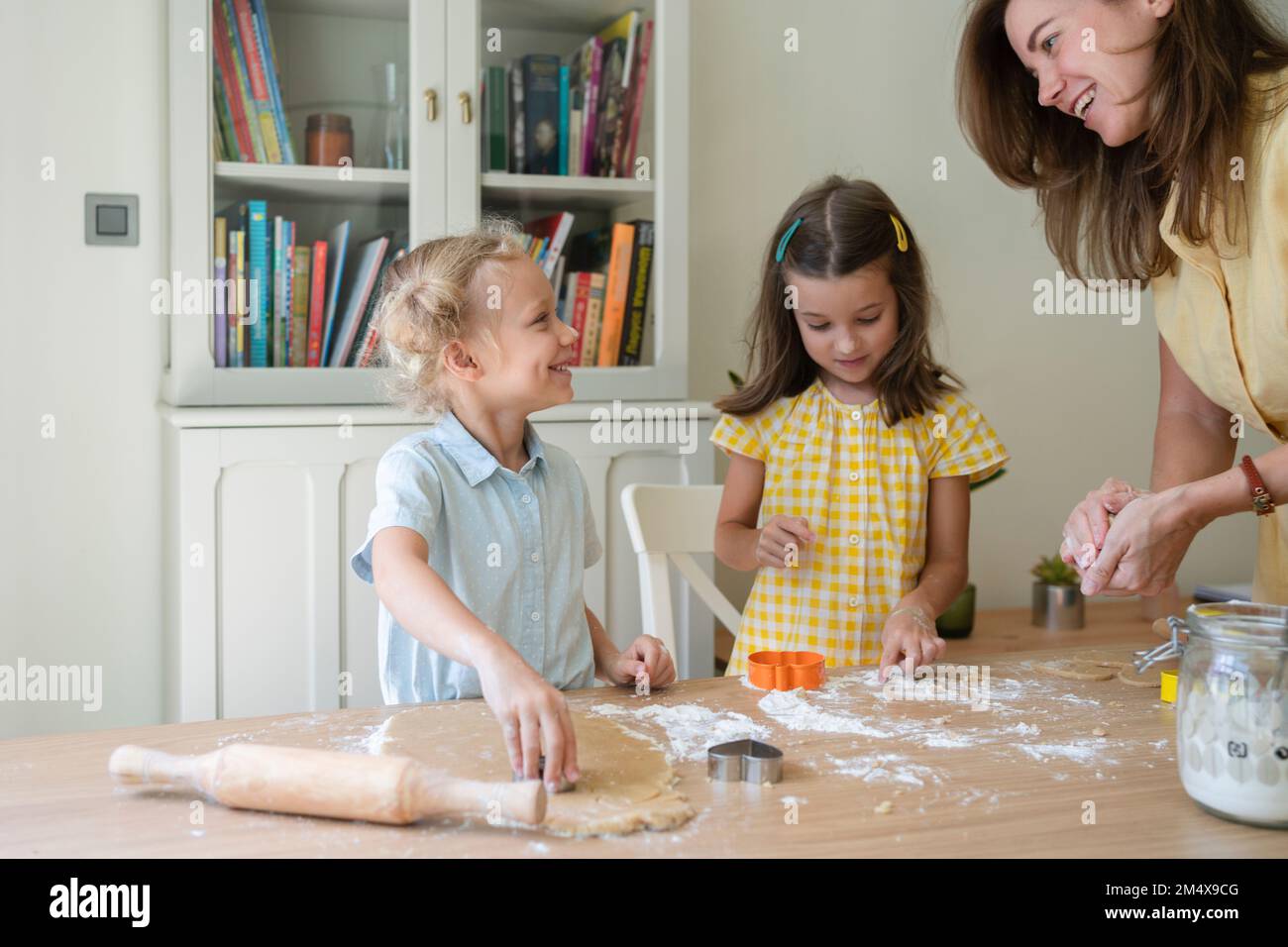 Glückliche Frau mit Mädchen, die zu Hause Kekse zubereiten Stockfoto