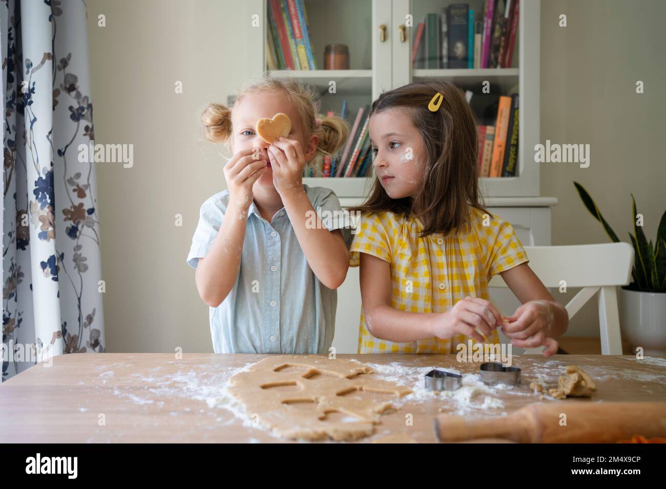 Mädchen, die zu Hause Kekse mit Teig zubereiten Stockfoto