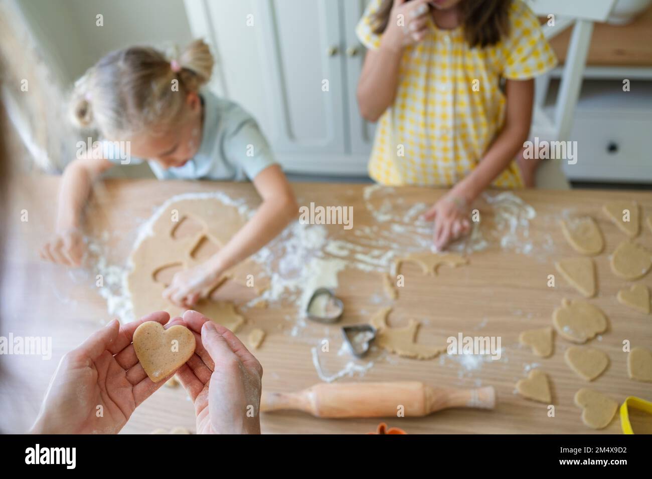 Hände einer Frau, die Kekse mit Mädchen zuhause zubereitet Stockfoto