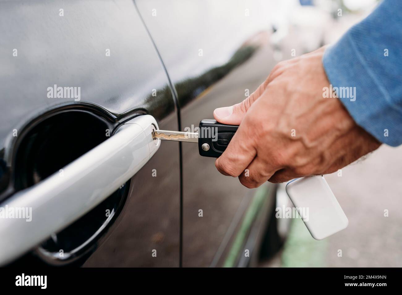 Hand eines Mannes, der das Auto mit dem Schlüssel verriegelt Stockfoto
