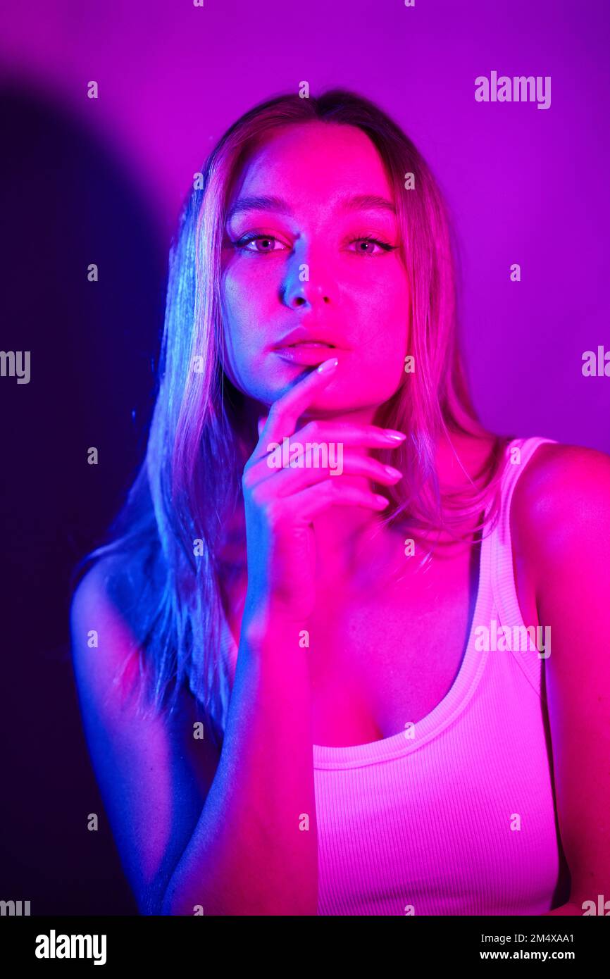 Junge Frau mit der Hand auf dem Kinn vor der Wand Stockfoto
