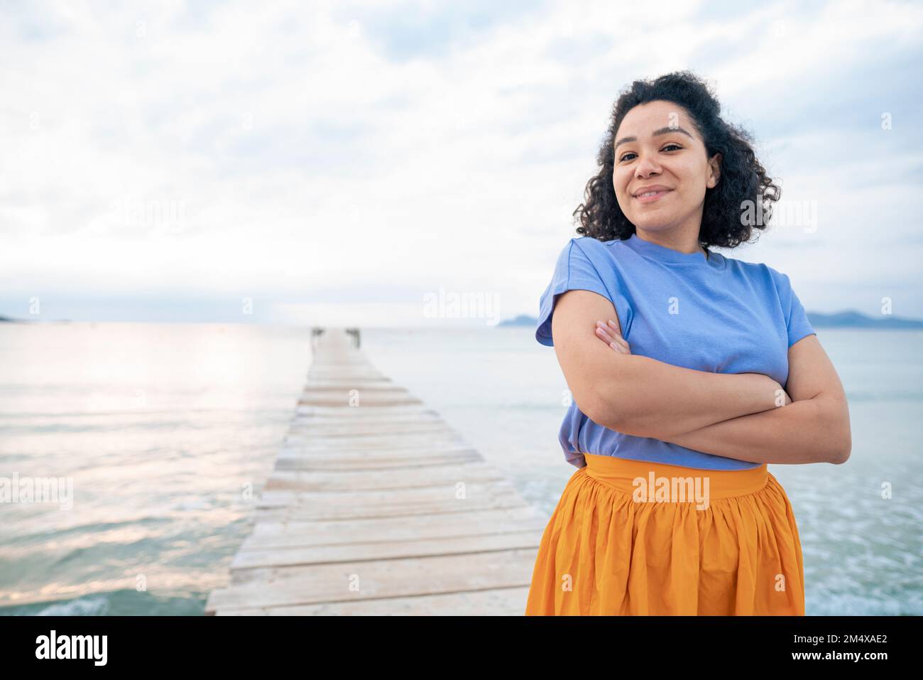 Eine lächelnde Frau, die die Arme überquerte, mitten im Meer Stockfoto