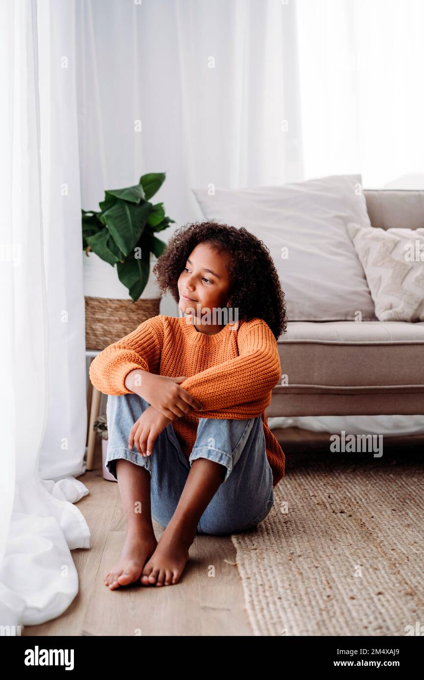Ein aufmerksames Mädchen, das zu Hause im Wohnzimmer sitzt Stockfoto