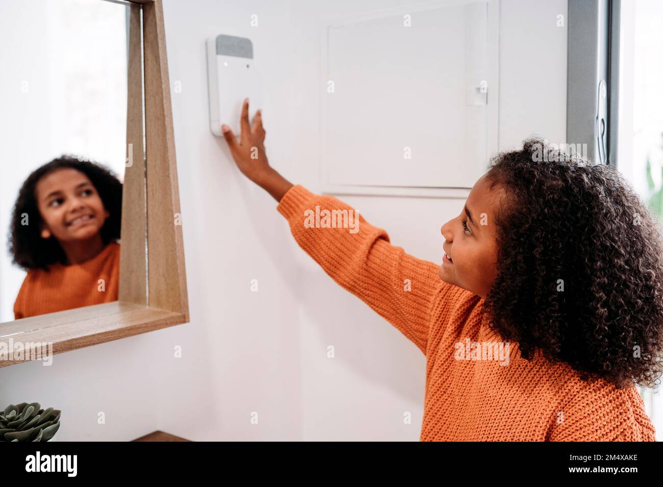 Glückliches Mädchen, das zu Hause einen Code in die Alarmanlage steckt Stockfoto