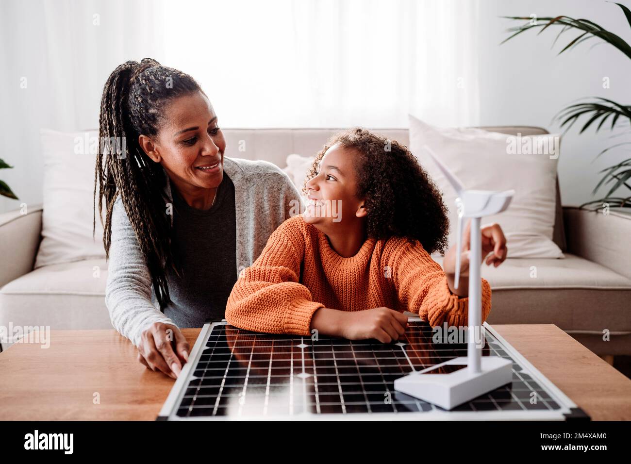 Glückliche Mutter und Tochter sitzen zu Hause mit erneuerbaren Energien Stockfoto