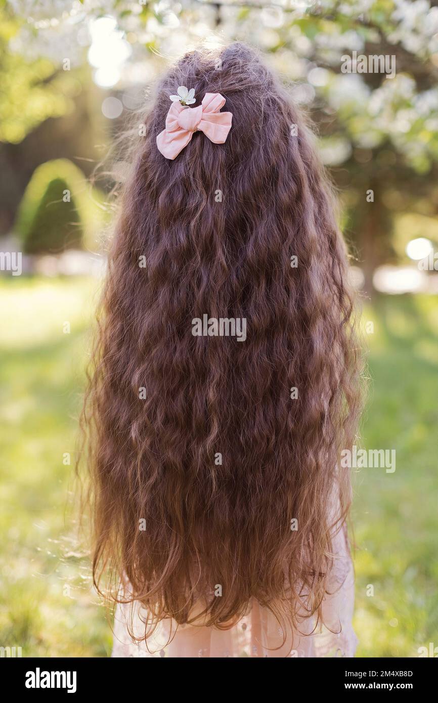 Ein Mädchen mit langen, welligen Haaren und rosa Schleife Stockfoto