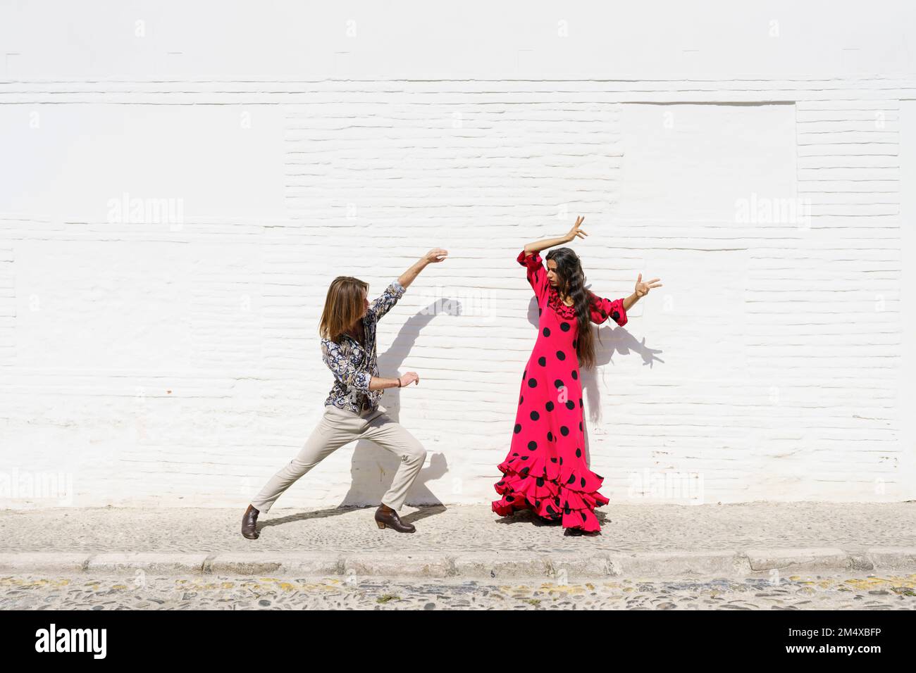 Tänzer führen an sonnigen Tagen vor der weißen Wand Flamenco auf Stockfoto
