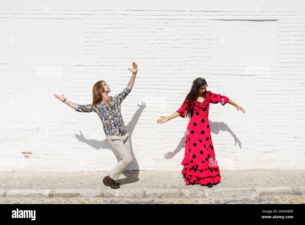 Flamenco-Tänzer treten an sonnigen Tagen vor der weißen Mauer auf Stockfoto