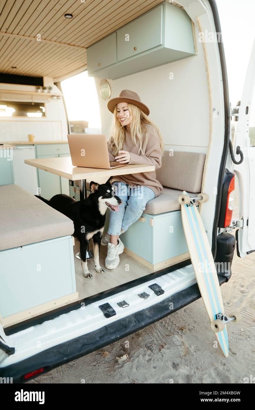 Freiberufler mit Hund, der im Wohnmobil an einem Laptop arbeitet Stockfoto