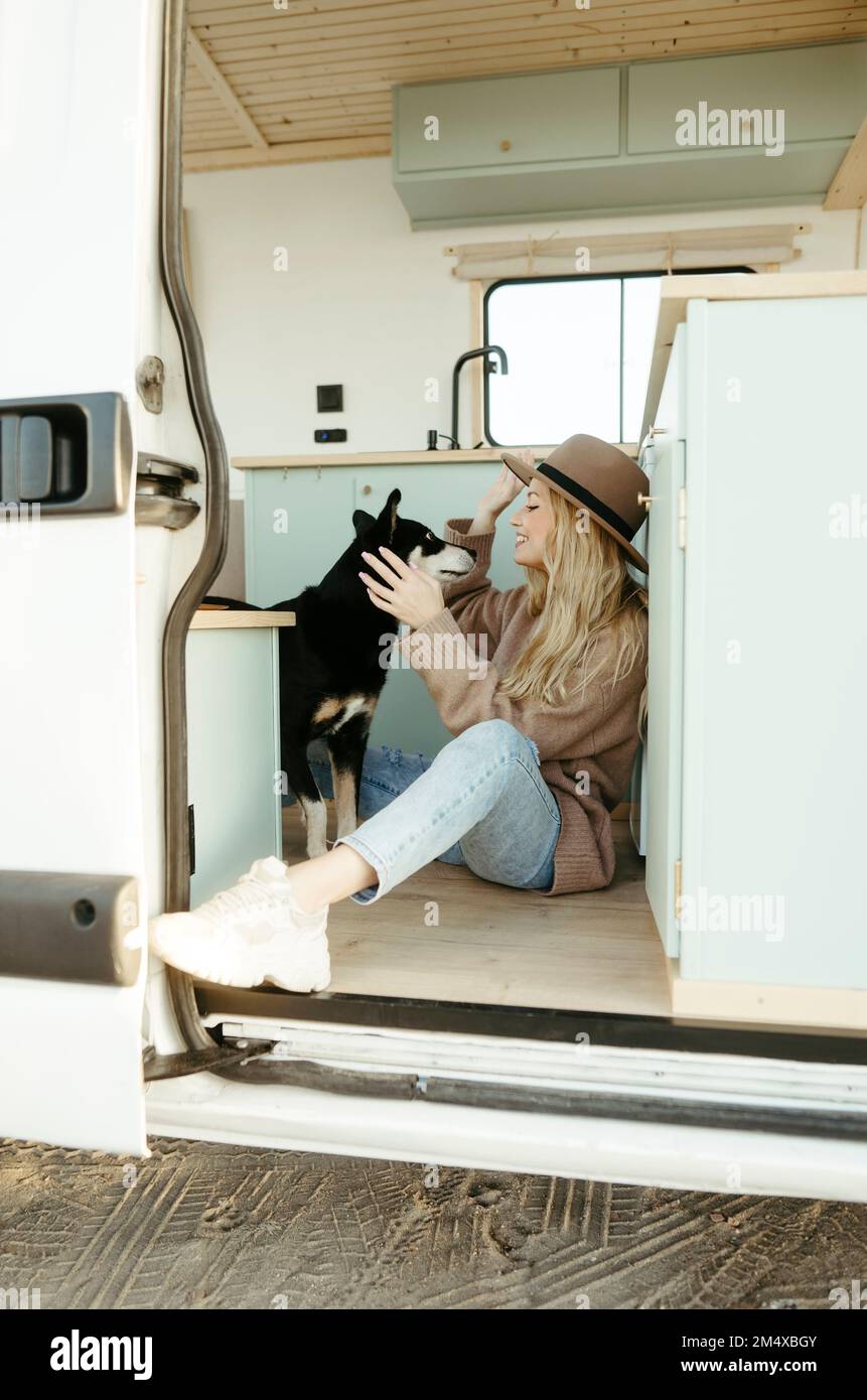 Junge Frau, die im Wohnmobil mit dem Hund spielt Stockfoto